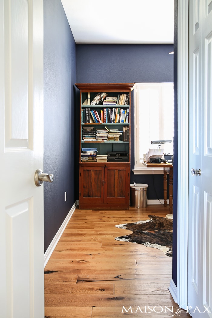 deep navy blue office with rustic wood floors, lots of bookcases, and an eclectic, collected vibe